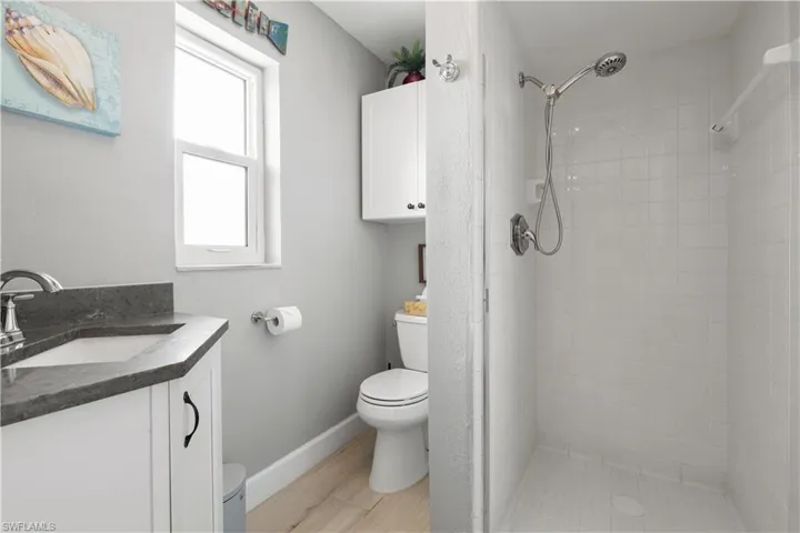 3rd Bathroom featuring quartz counter, tile with walk in glass shower door.