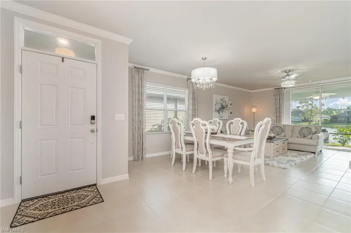 Tiled dining space with ornamental molding and ceiling fan with notable chandelier