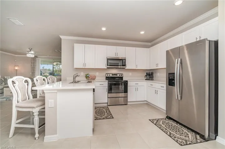 Kitchen featuring sink, kitchen peninsula, stainless steel appliances, white cabinets, and a breakfast bar