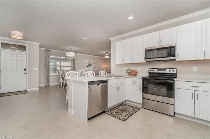 Kitchen featuring ornamental molding, white cabinets, kitchen peninsula, and stainless steel appliances