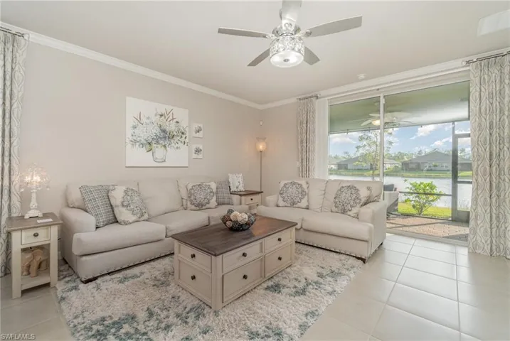 Tiled living room with a water view, crown molding, and ceiling fan