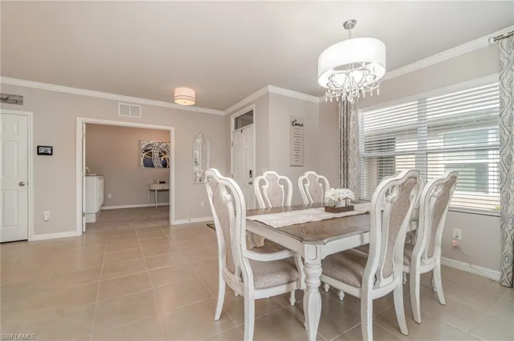 Dining space featuring ornamental molding, a chandelier, and light tile patterned flooring