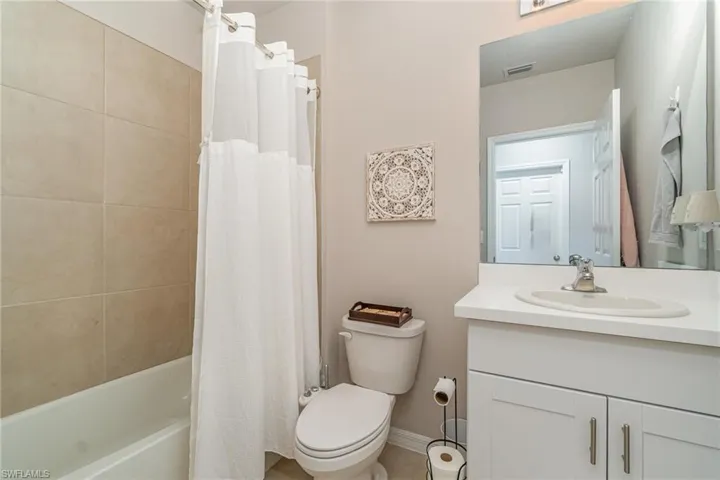 Full bathroom with vanity, shower / bath combo with shower curtain, and toilet