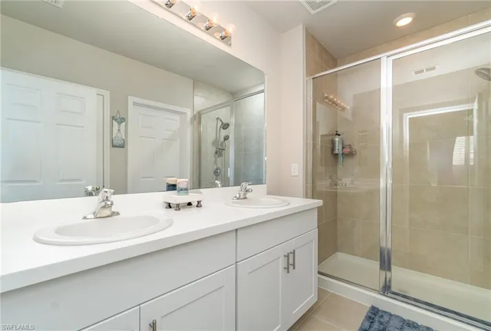 Bathroom with vanity, tile patterned flooring, and an enclosed shower