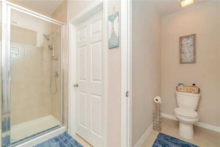 Bathroom featuring toilet, a shower with shower door, and tile patterned flooring