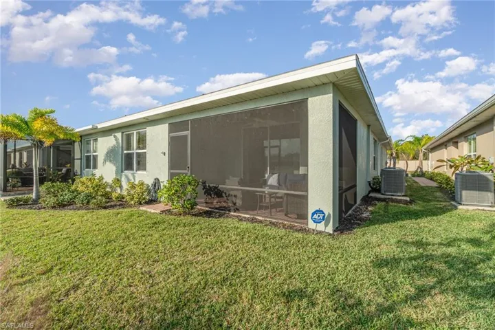 Rear view of house featuring a yard, a sunroom, and cooling unit