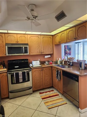 Kitchen featuring stainless steel appliances, ceiling fan, dark countertops, and light tile patterned floors