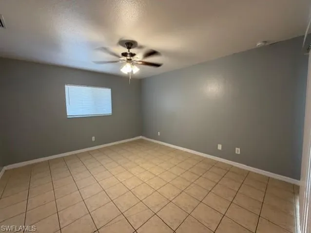 Unfurnished room with a textured ceiling, ceiling fan, and light tile patterned flooring