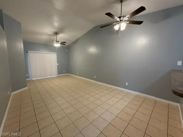 Spare room with vaulted ceiling, light tile patterned floors, and a ceiling fan