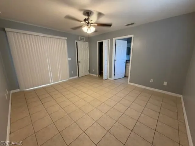 Unfurnished bedroom featuring a ceiling fan, light tile patterned floors, and connected bathroom