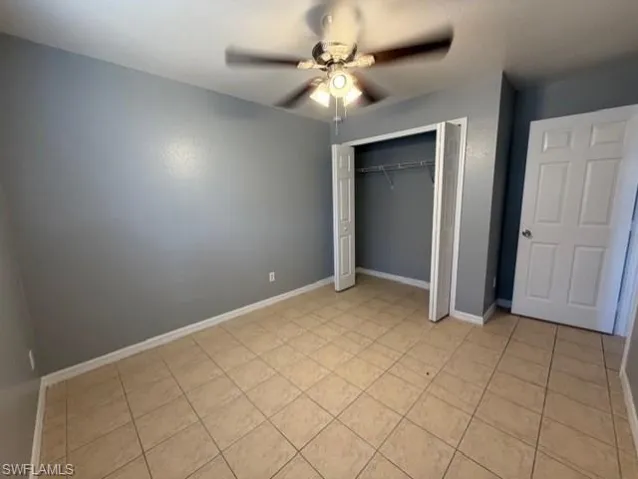 Unfurnished bedroom with a ceiling fan, a closet, and light tile patterned flooring