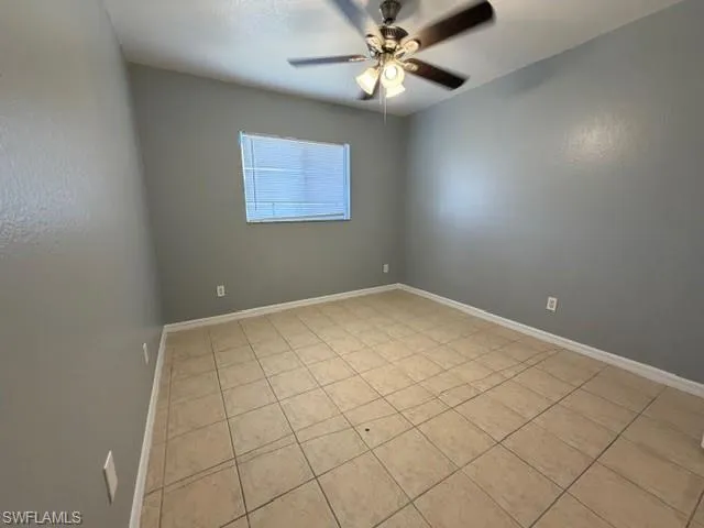 Empty room featuring light tile patterned floors and a ceiling fan
