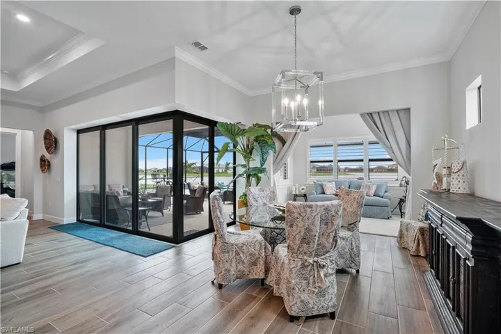 Dining space featuring an inviting chandelier, ornamental molding, hardwood / wood-style flooring, and a raised ceiling