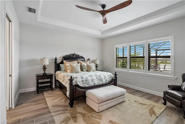 Bedroom featuring a tray ceiling, wood-type flooring, and ceiling fan