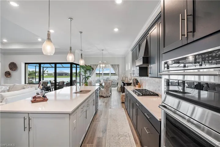 Kitchen featuring stainless steel appliances, hardwood / wood-style floors, tasteful backsplash, and a kitchen island with sink