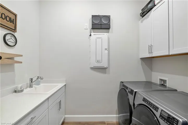Laundry area with washing machine and dryer, washer hookup, sink, hardwood / wood-style flooring, and cabinets