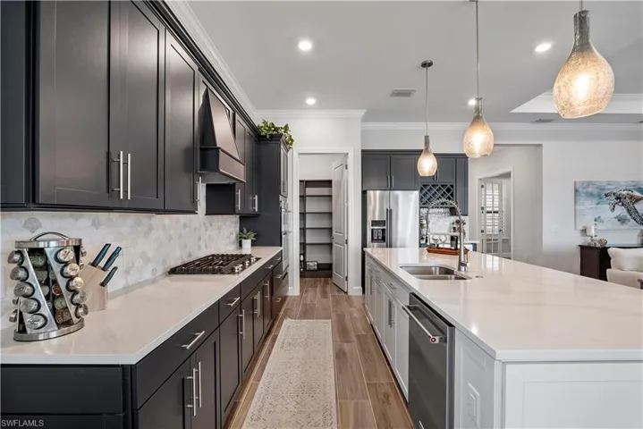 Kitchen featuring hanging light fixtures, appliances with stainless steel finishes, premium range hood, a large island, and tasteful backsplash