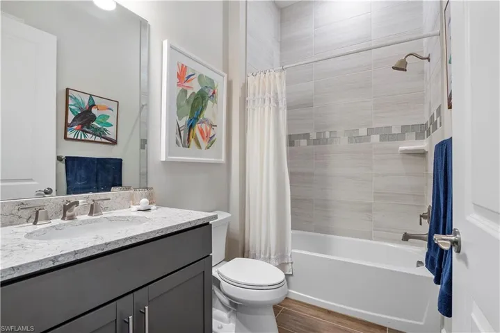 Full bathroom with shower / bath combo with shower curtain, oversized vanity, and toilet