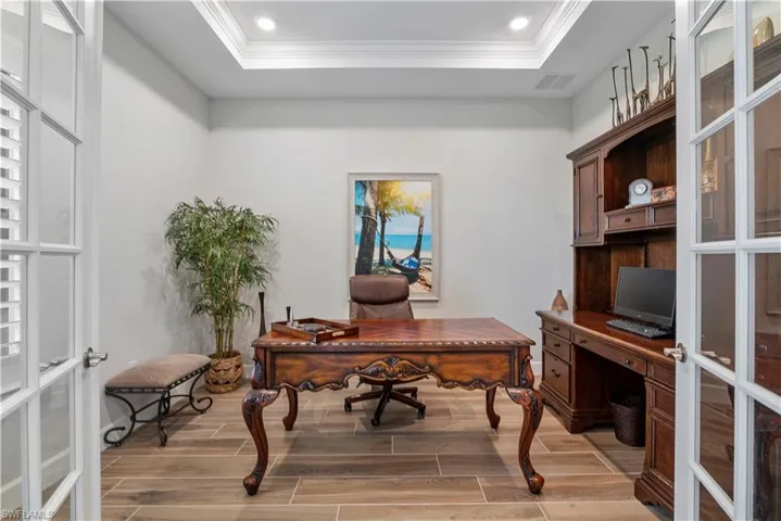 Office area featuring a raised ceiling, hardwood / wood-style flooring, french doors, and crown molding