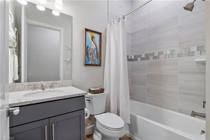 Full bathroom featuring shower / bath combination with curtain, toilet, and vanity with extensive cabinet space