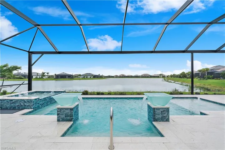 View of pool featuring glass enclosure, pool water feature, an in ground hot tub, and a water view