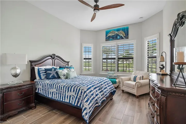 Bedroom featuring ceiling fan, multiple windows, and wood-type flooring