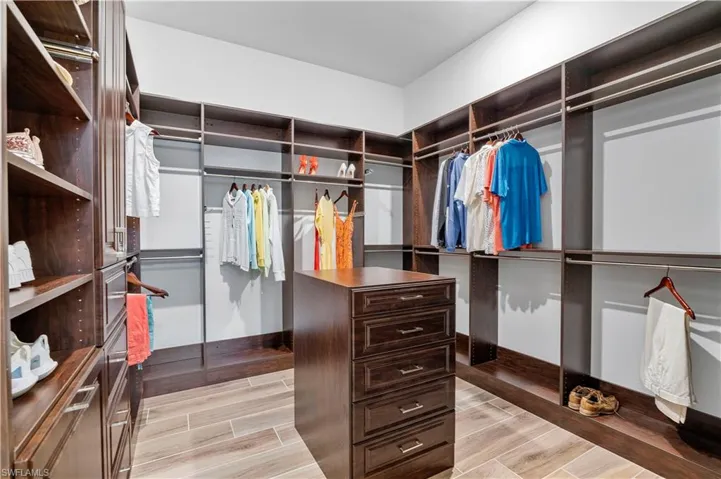 Walk in closet with light hardwood / wood-style flooring