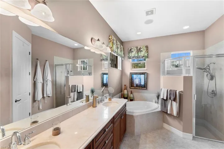 Bathroom featuring tile patterned flooring, dual bowl vanity, and separate shower and tub