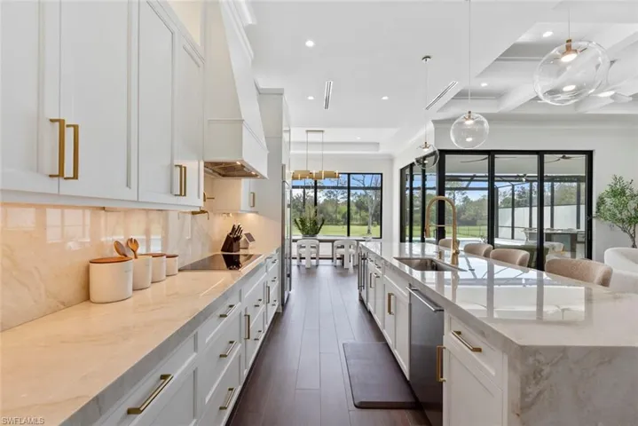 Kitchen with light stone counters, sink, dishwasher, and white cabinets