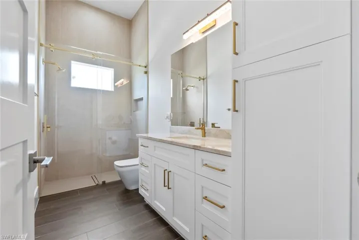 Bathroom featuring vanity, tiled shower, and toilet