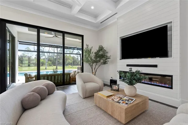 Living room with coffered ceiling, hardwood / wood-style flooring, ornamental molding, and beamed ceiling