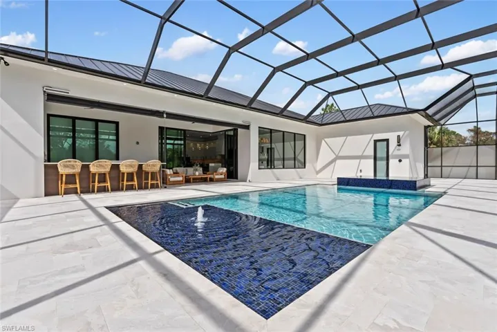 View of swimming pool with a patio, exterior bar, outdoor lounge area, pool water feature, and a lanai