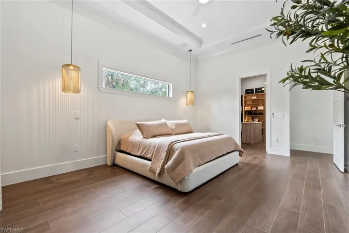 Bedroom with connected bathroom, dark hardwood / wood-style floors, and a raised ceiling
