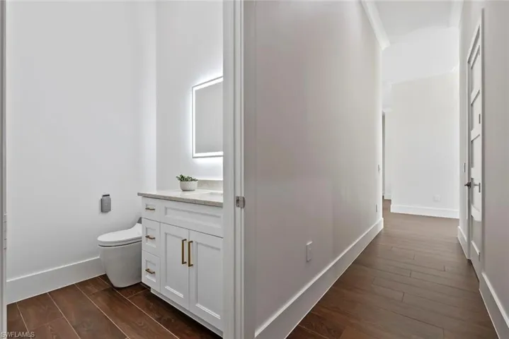 Half Bathroom with vanity, hardwood / wood-style floors, and toilet