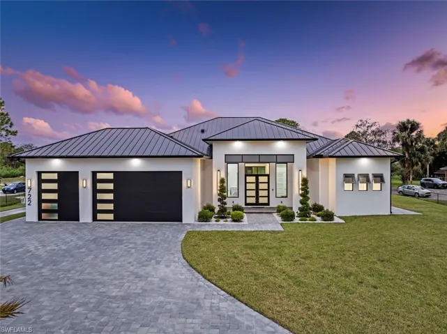 View of front of property featuring french doors, a yard, and a garage