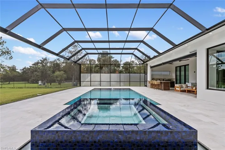 View of swimming pool with a lanai, a patio, a bar, an outdoor hangout area, and an in ground hot tub