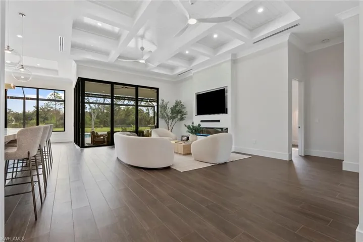 Living room with coffered ceiling, beam ceiling, dark wood-type flooring, and a high ceiling