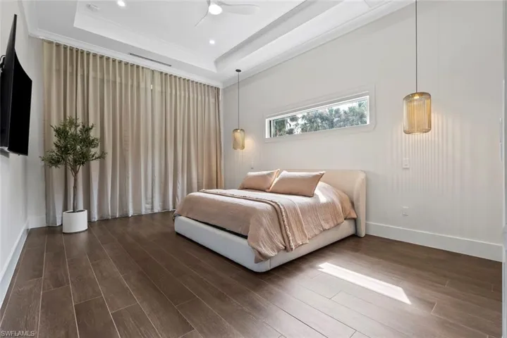 Bedroom featuring dark wood-type flooring, ceiling fan, and a raised ceiling