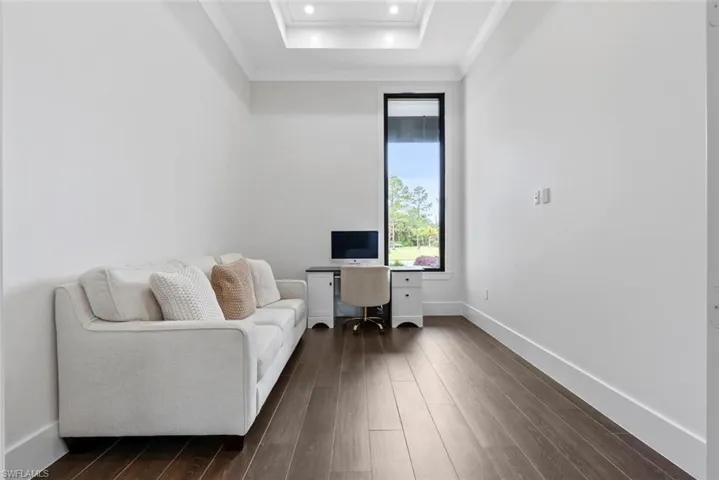 Office featuring crown molding, dark wood-type flooring, and a tray ceiling