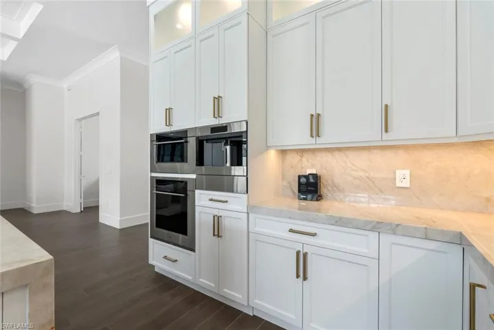 Kitchen with white cabinetry, ornamental molding, dark hardwood / wood-style floors, and tasteful backsplash
