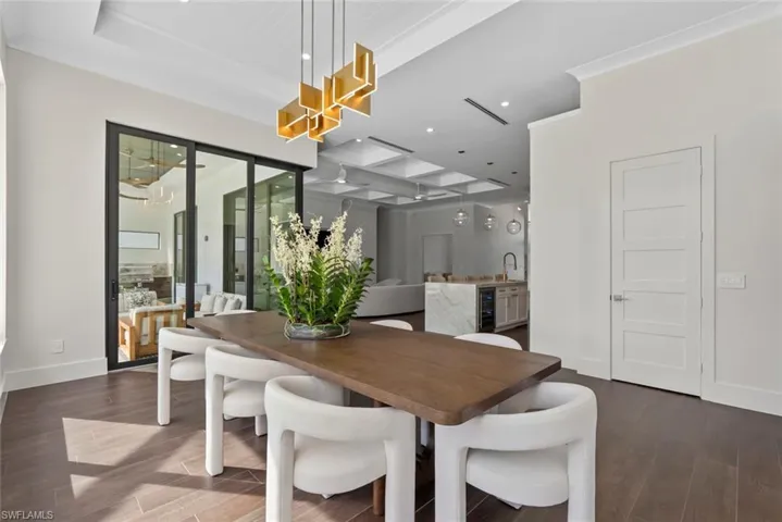 Dining area with crown molding, sink, dark wood-type flooring, and wine cooler