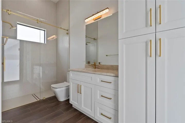 Bathroom featuring vanity, a shower with door, and toilet
