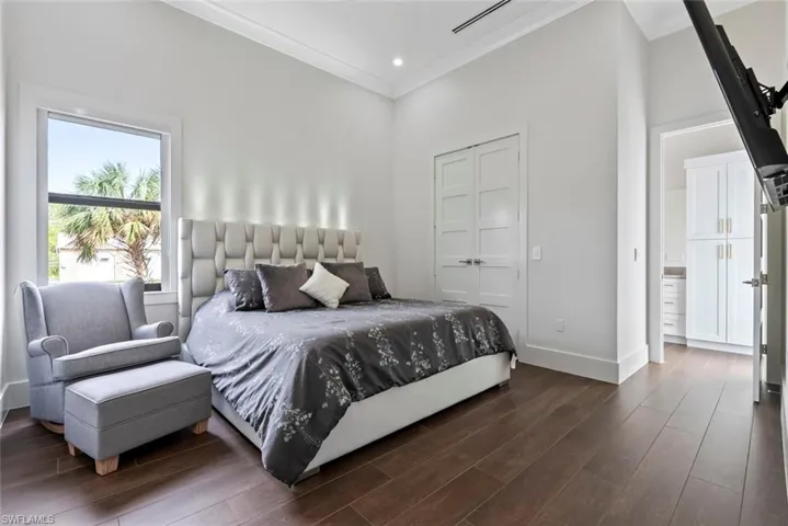 Bedroom featuring dark wood-type flooring, ornamental molding, and a closet