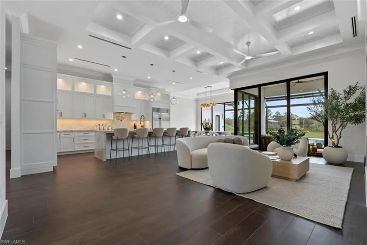 Living room featuring coffered ceiling, dark wood-type flooring, beamed ceiling, and ceiling fan