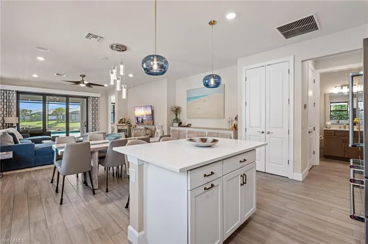 Kitchen featuring white cabinetry, decorative light fixtures, a kitchen island, ceiling fan, and light hardwood / wood-style floors