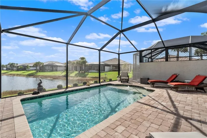 View of pool with a water view, glass enclosure, and a patio area