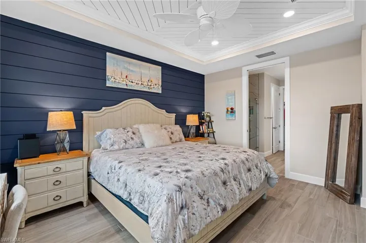 Bedroom with ornamental molding, a raised ceiling, ceiling fan, and light wood-type flooring