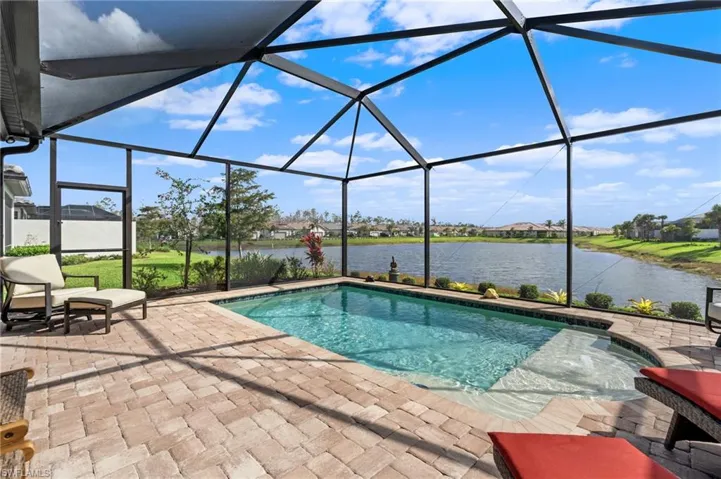 View of pool with a water view, a patio, and glass enclosure