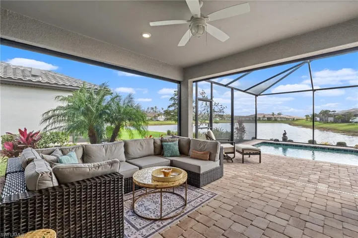 View of patio / terrace featuring an outdoor living space, ceiling fan, glass enclosure, and a water view