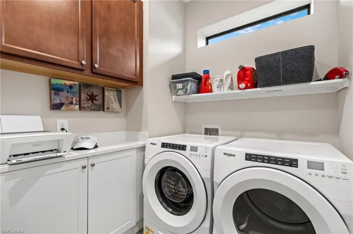 Washroom with cabinets and washing machine and clothes dryer